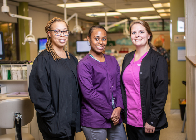 Three team members posing for a photo at their dental hygienist jobs in a D4C-affiliated practice